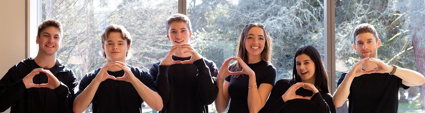 A group of attendees at an Oregon Innovation Challenge workshop pose for a group photo and make the "O" symbol with their hands.