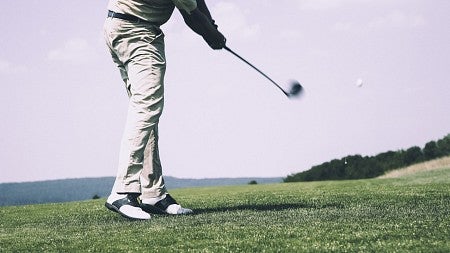 A person golfing captured mid-swing