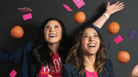 Jana Chapman (left) and Alyssa McKee (right) laugh as they throw grapefruits and business cards up into the air around themselves