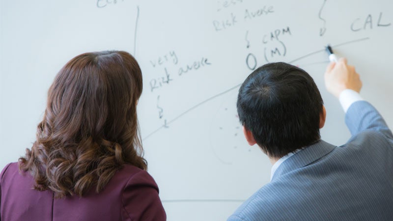 Concurrent MBA/MSF A student and professor discuss work on a whiteboard