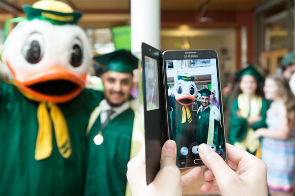 Lillis Commencement Reception Photo of a student being photographed with cell phone during the Lillis commencement reception