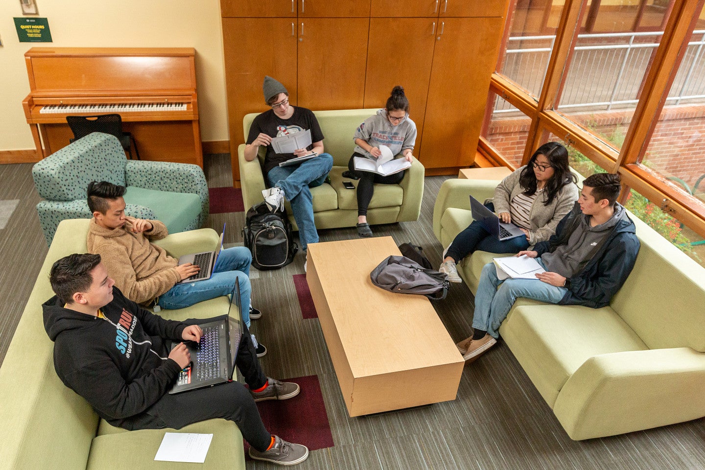 Group of students sitting on sofas studying and talking in the Business Academic Residential Community.