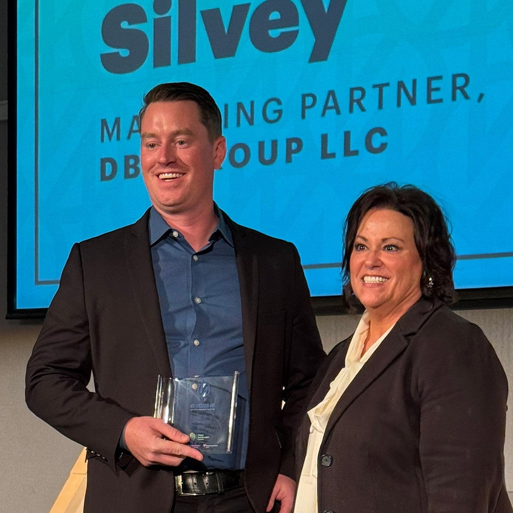 Daniel Silvey '14, MBA '23, poses with his award onstage at Portland Business Journal's 40 under 40 luncheon.