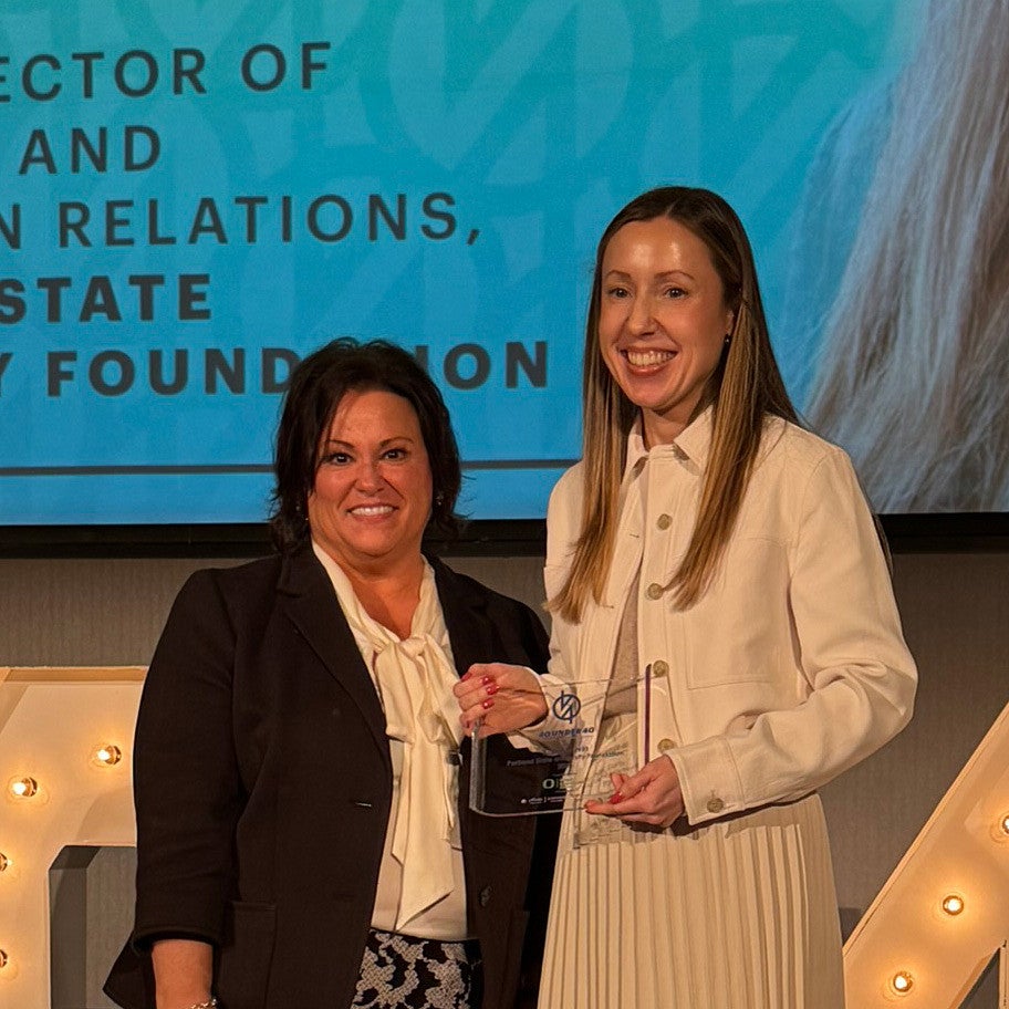 Katie Slavin, MBA '19, poses with her award onstage at Portland Business Journal's 40 under 40 luncheon.