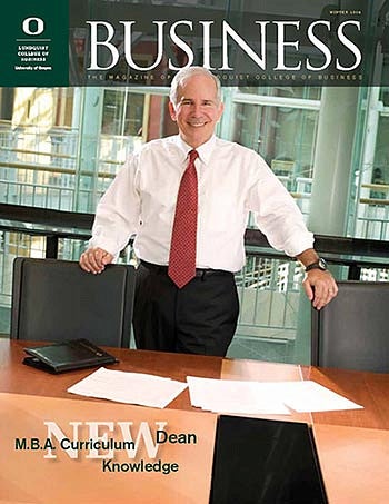 Cover image of magazine issue featuring a portrait of Dean Dennis Howard standing over a conference table full of papers and portfolios with his shirt sleeves rolled up, ready to get to work