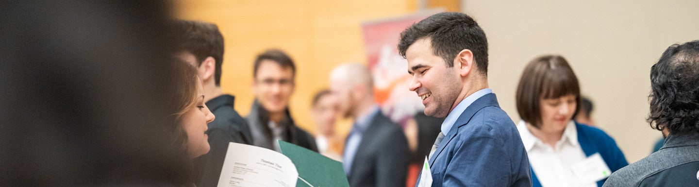 A crowd of students and companies standing and mingling at a networking event.