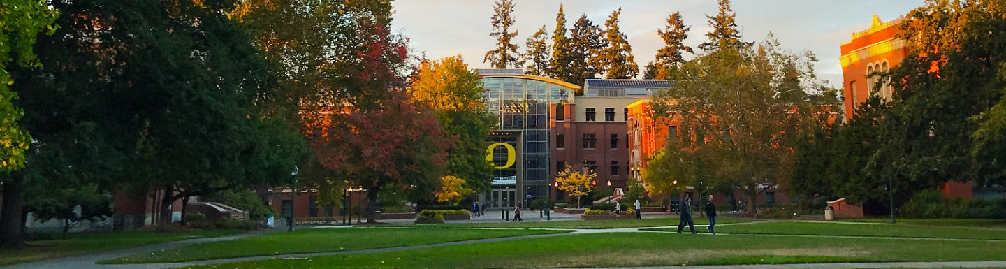 An exterior photo of the Lillis Business Complex from across the quad during a summer sunset