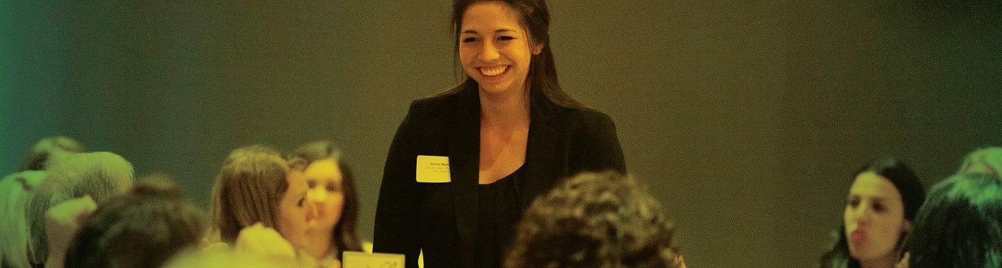 A student rises from her table at the Women in Business gala