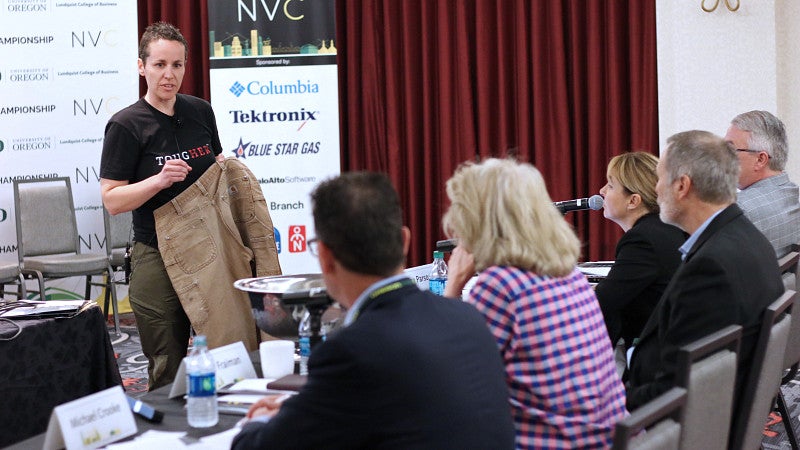 Student presenting in front of a panel of judges at a New Venture Championship competition.