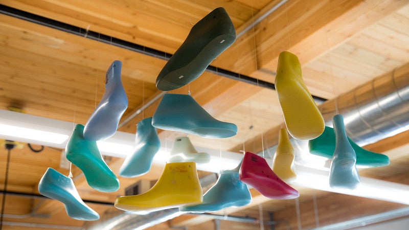 Multiple different-colored shoe molds hanging from a wooden ceiling