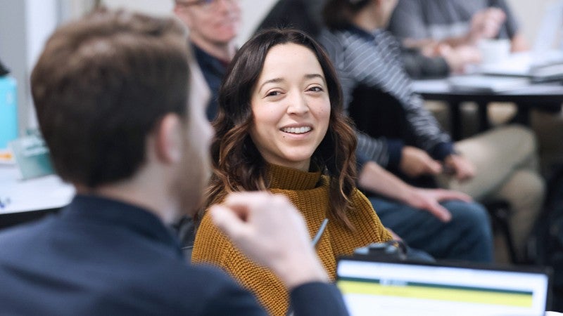 Close-up of two students in a classroom smiling at each other