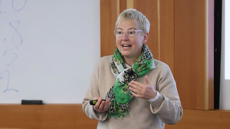 Professor standing in front of classroom talking and gesturing