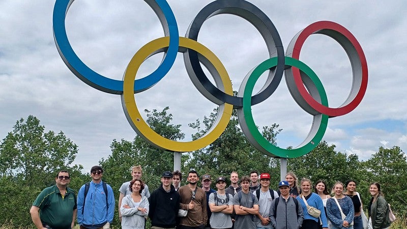 UO instructor Yoav Dubinsky and a group of sports business students stand beneath a statue of the Olympic rings in London