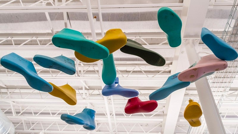 Multiple different colored shoe molds hanging from a ceiling in an artistic way