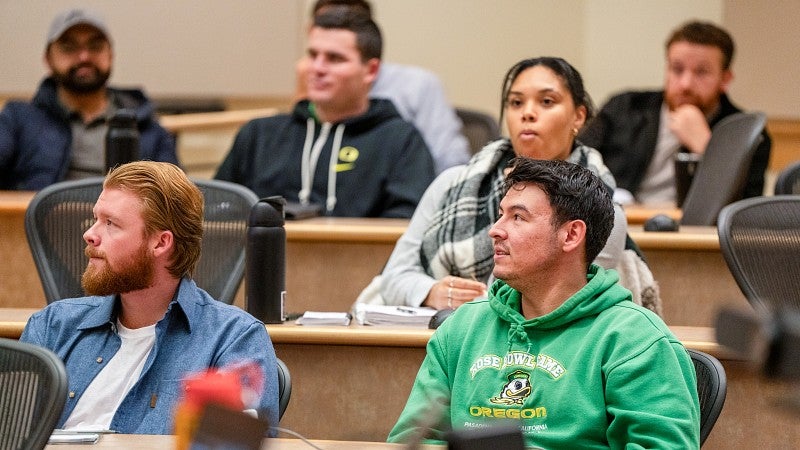 A classroom full of students sitting at desks and looking off to one side