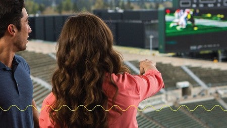 Two young people look out over a football field