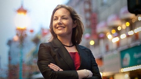 Anika Hedstrom stands with arms crossed outside on a busy city street