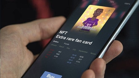 Close up photo of a hand holding a smart phone, on which a sports NFT is displayed