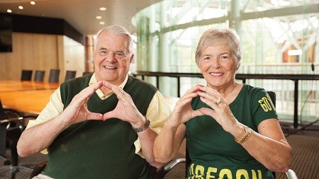 Gerry and Marilyn Cameron, sitting in the board room in the Lillis Business Complex, make the “O” symbol with their hands
