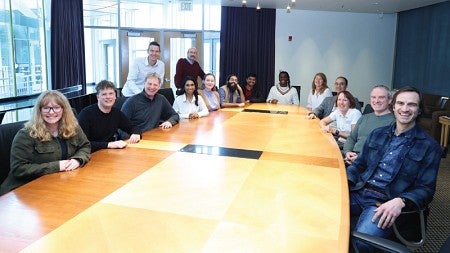 UO management faculty pose for a group photo around the board room table in the Lillis Business Complex