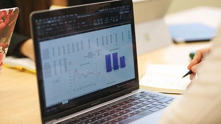 Close-up photo of a laptop screen on which a dashboard with several graphs and columns of data is displayed