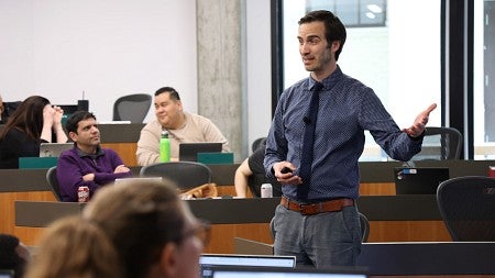 A student stands and speaks to their peers in a classroom