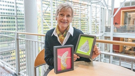 Marketing professor T. Bettina Cornwell holds up the art that she has created with fruit stickers