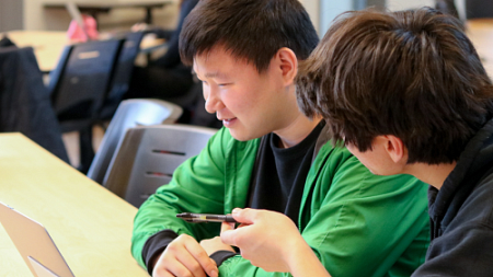 Two students talking together at a table