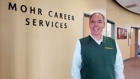 Dean Bruce Blonigen stands in front of signage for Mohr Career Services