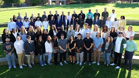 The SPM Class of 2026 stands outside on the new UO Portland campus on a sunny day