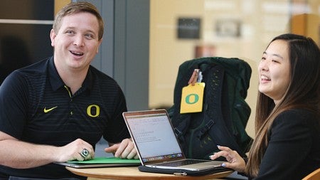 Two students with laptops interacting