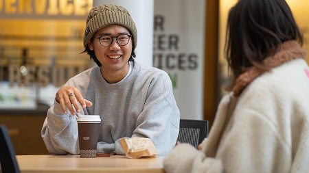 Two students enjoy coffee in the atrium