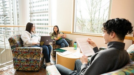 Four students gather for community and collaboration around a nook in the Lillis Business Complex