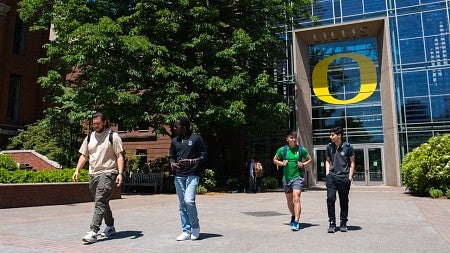 Four students walk away from the south entrance to the Lillis Business Complex on a sunny day