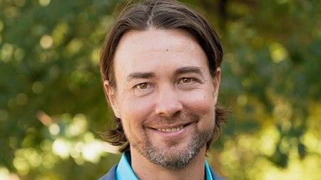 Portrait photo of Jake Weatherly with green trees in the background
