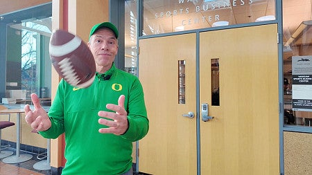 Dean Bruce Blonigen, standing in front of the doors to the Warsaw Sports Business Center, spins a football in his hands