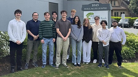 A group of students stand outside in front of an Oregon Pacific Bank building
