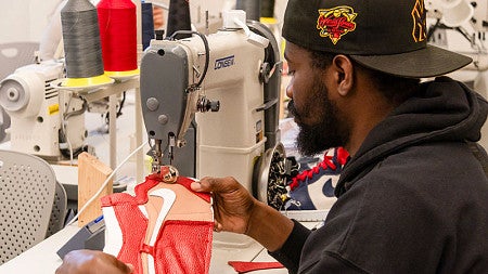A Sports Product Management student sews a shoe design using a sewing machine