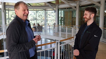 Management professor Ralph Heidl laughs while talking to another person