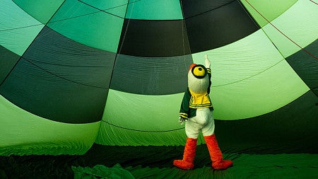 The Oregon Duck mascot looks up at the inside of a hot air balloon