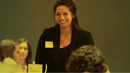 A student rises from her table at the Women in Business gala