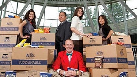 Cover image with students sitting and standing among boxes of Kettle Potato Chips with the text underneath them that says "Beyond Blue Chips"