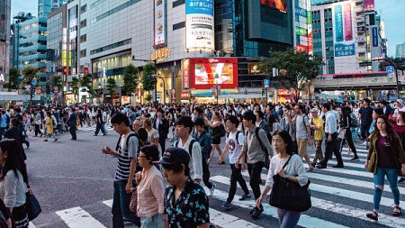 A crowd of people cross a large crosswalk in Tokyo