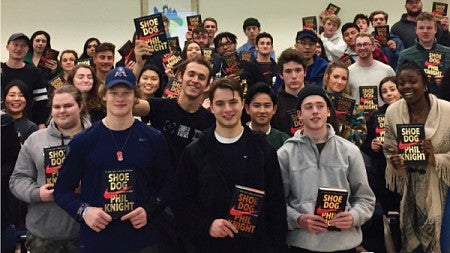 Students pose holding Phil Knight's Shoe Dog book