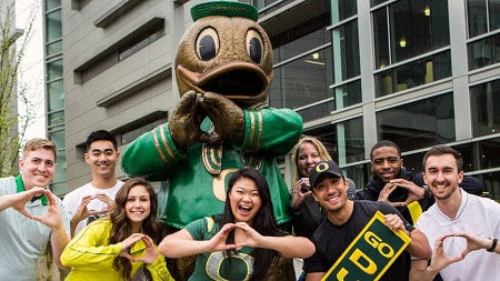 A group of students throw the O in front of the Duck statue