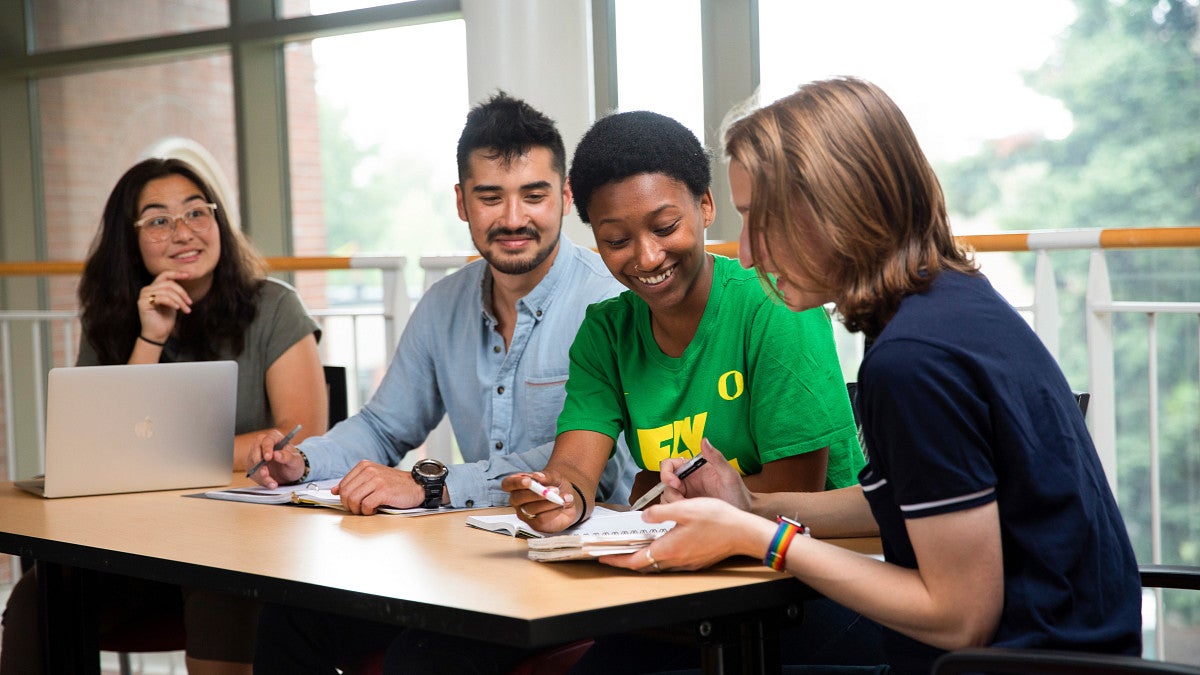 Three students sitting at a table working together in the Lillis Business Complex.