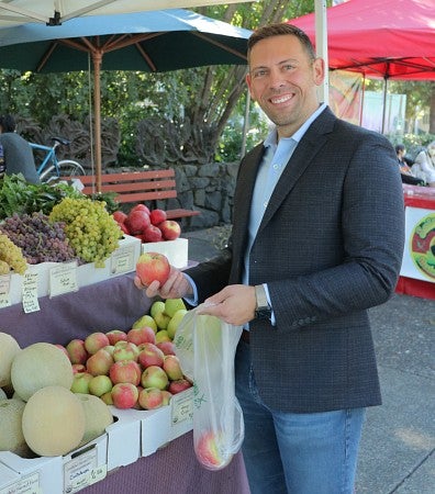 Josh Beck smiles as he bags apples at a Eugene farmer's market