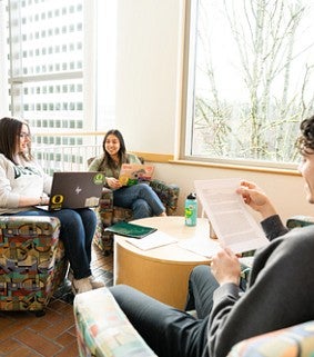 Four students gather for community and collaboration around a nook in the Lillis Business Complex