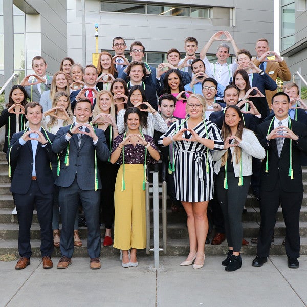 A group photo of business honors students standing on the steps of the Ford Alumni Center and holding their hands in an O shape..