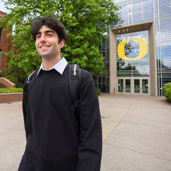 Student walking outside away from the Lillis Business Complex with the building in the background